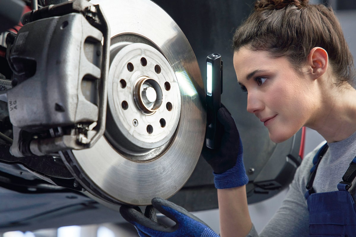 KFZ Mechanikerin überprüft Bremse
