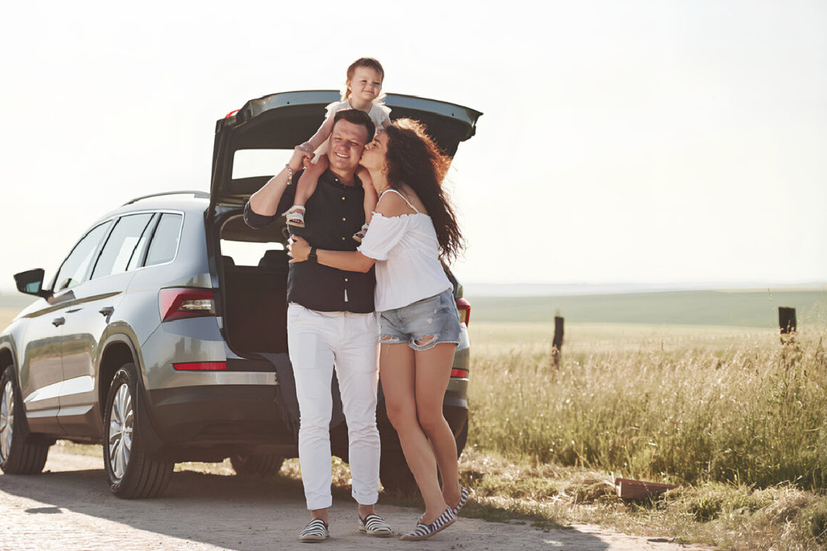 Familie steht auf einer Landstraße vor ihrem Fahrzeug